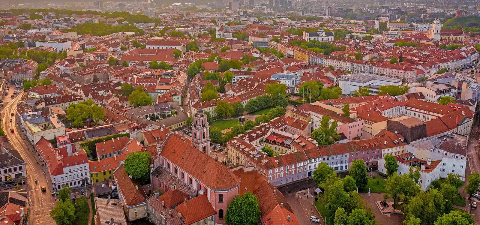 Aerial view of the red-roofed Old Town of Vilnius in early morning light, with the modern business district on the skyline.