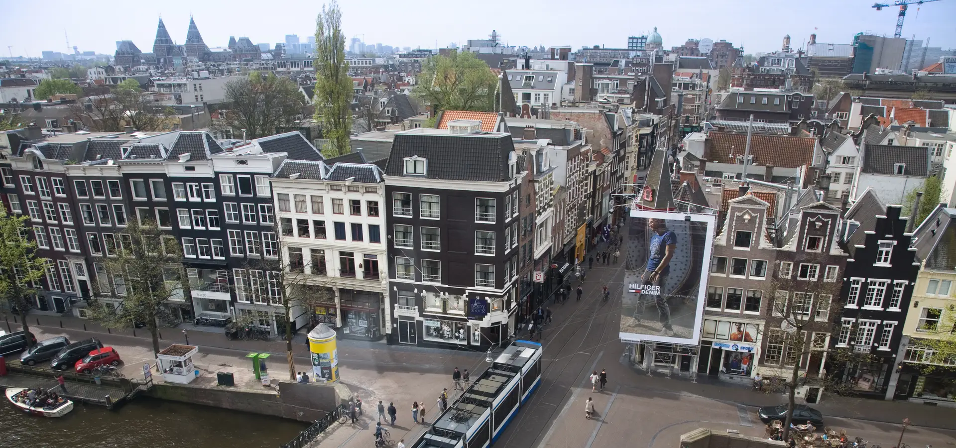 Rooftop view over the Keizersgracht canal in central Amsterdam, lined with tall gabled canal houses and trees.