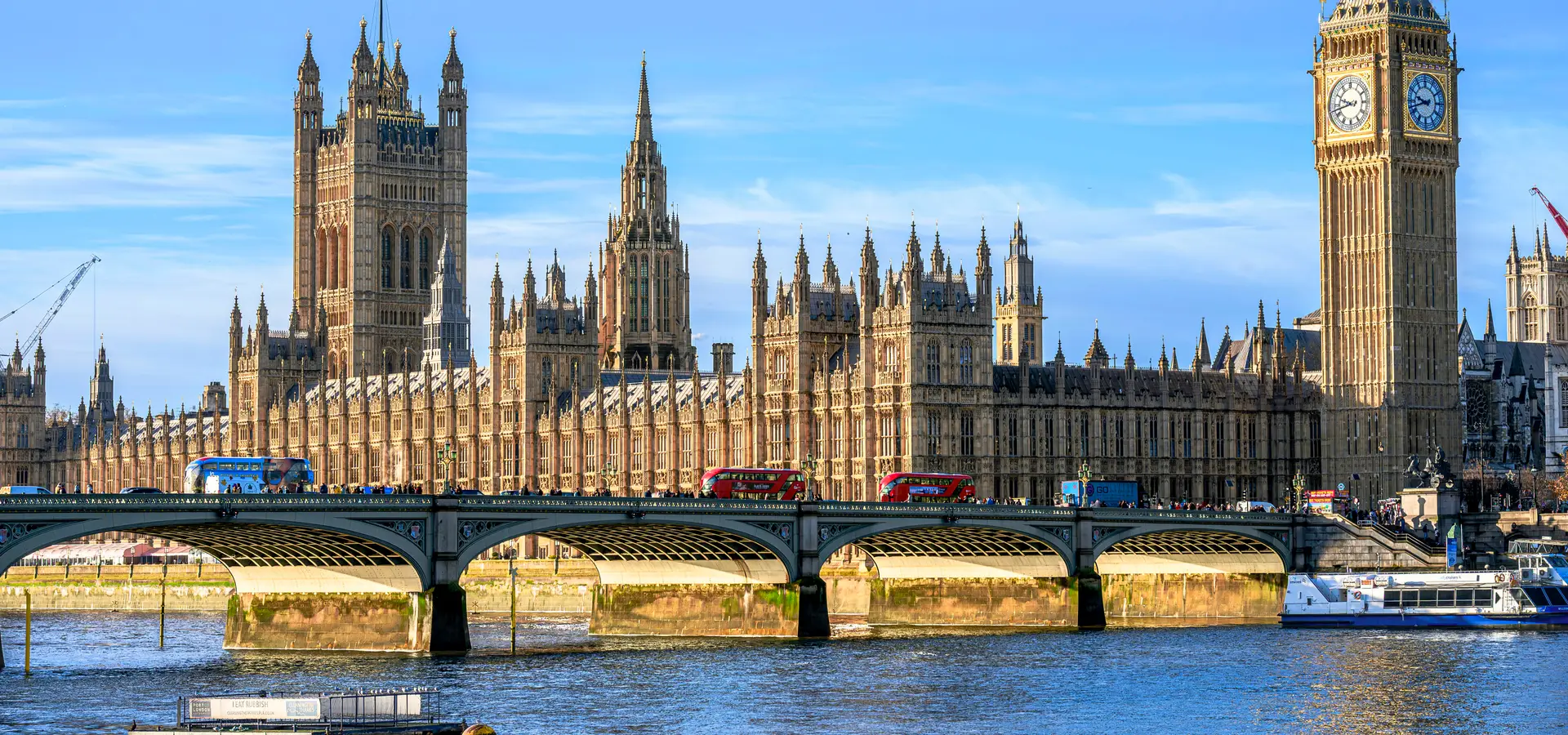 The Houses of Parliament and the Elizabeth Tower (Big Ben) in London, seen across the River Thames and Westminster Bridge on a sunny day.